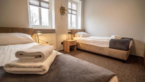 two beds in a room with two windows and towels at Villa Pallas in Olsztyn