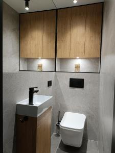a bathroom with a sink and a toilet and cabinets at Apartament 3 Maja 4 in Gorlice