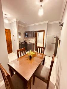 a kitchen with a wooden table with chairs and a refrigerator at KAMAL HOTEL APARTMENTS in Mansoura