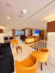 KAMAL HOTEL APARTMENTS في المنصورة: غرفة معيشة مع أريكة سوداء وكراسي برتقالية