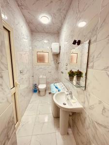 Baño blanco con lavabo y aseo en KAMAL HOTEL APARTMENTS, en El Mansurá