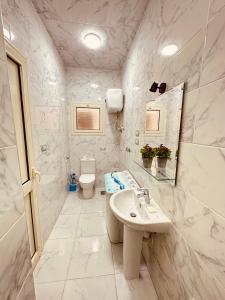 a white bathroom with a sink and a toilet at KAMAL HOTEL APARTMENTS in Mansoura