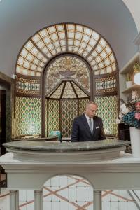 Un uomo in giacca e cravatta seduto al bancone di Hotel Marisa a Roma