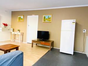 a living room with a refrigerator and a tv at Mid Valley Motel in Morwell