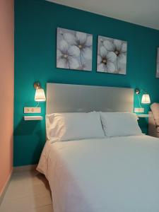 a bedroom with a white bed with three pictures on the wall at Estudios La Casina in Cáceres