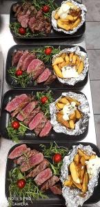 quatro bandejas de alimentos com carne e legumes sobre uma mesa em Guesthouse Pr'Šefu em Brezice