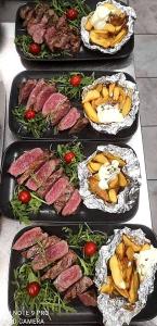 four trays of food with meat and vegetables on a table at Guesthouse Pr'Šefu in Brežice