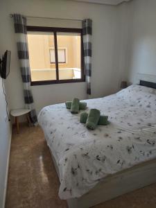 een slaapkamer met een bed met groene kussens en een raam bij Costamarina Apartments in Cabo Roig