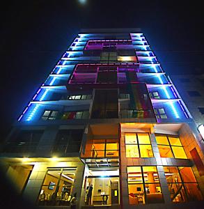 un edificio alto con luces azules por la noche en Hôtel Fleur de Lys Plateau, en Dakar