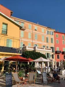 a building with chairs and umbrellas in front of it at Lovely studio - heart of Menton, near the beach. in Menton