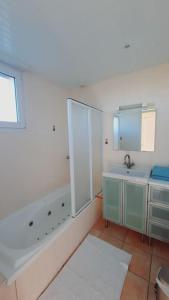 La salle de bains est pourvue d'une baignoire, d'un lavabo et d'un miroir. dans l'établissement Maison La Denolais Carnet Mont-Saint-Michel, à Saint-James