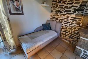 - un canapé dans une chambre dotée d'un mur en pierre dans l'établissement Maison La Denolais Carnet Mont-Saint-Michel, à Saint-James