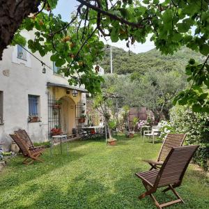 einen Hof mit zwei Stühlen und einem Haus in der Unterkunft Casa Olivia Lacremà in Finale Ligure