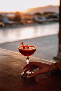 a woman holding a red drink in a martini glass at Ammothines Cycladic Suites in Naxos Chora