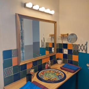 een badkamer met een spiegel en een bord op een aanrecht bij Bambou in Autun