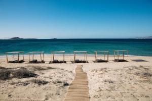 a wooden boardwalk on the beach with a group ofuts at Ammothines Cycladic Suites in Naxos Chora
