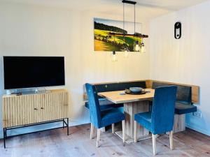 a dining room table with blue chairs and a television at Ferienwohnung Niki in Titisee-Neustadt