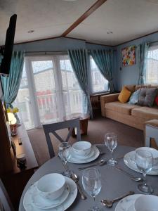 a living room with a table with plates and wine glasses at Vista Caravan Hire in Seasalter