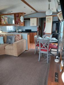 a living room and kitchen with a couch and a table at Vista Caravan Hire in Seasalter