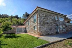 ein großes Steinhaus mit einem Rasenhof in der Unterkunft Casa da Boavista Camélias de Basto-Turismo Rural in Celorico de Basto