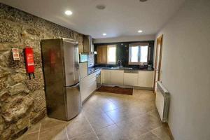 a kitchen with a refrigerator and a stone wall at Casa da Boavista Camélias de BastoTurismo Rural in Celorico de Basto