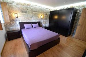 ein Schlafzimmer mit einem Bett und einer Steinwand in der Unterkunft Casa da Boavista Camélias de Basto-Turismo Rural in Celorico de Basto + 30 Fotos