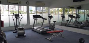 a gym with several tread machines in a room with windows at The Wave Apartment in Jakarta