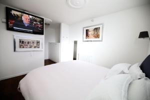 Schlafzimmer mit einem weißen Bett und einem Flachbild-TV in der Unterkunft "Fall in love only" Morcote lake in Morcote