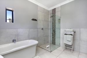 2 On Lismore Guesthouse في توكاي: حمام مع حوض استحمام ودش زجاجي