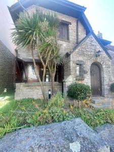 a stone house with a palm tree in front of it at Precioso Chalet Vista Mar in Mar del Plata