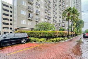 ジャカルタにあるRedLiving Apartemen Sunter Park View - Emma Roomsの建物前の駐車場に停めた黒いバン