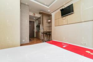 Habitación con cama y TV en la pared. en RedLiving Apartemen Sunter Park View - Emma Rooms, en Yakarta