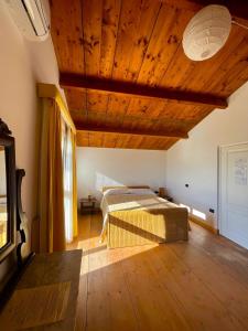 sypialnia z łóżkiem i drewnianym sufitem w obiekcie La Tinaia Country House w mieście Magomadas