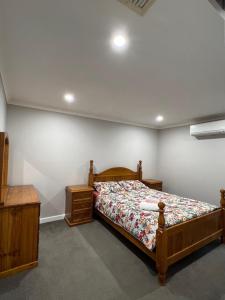 1 dormitorio con 1 cama, vestidor de madera y 1 cama sidx sidx sidx sidx en Free secure parking & WiFi in this Executive 3 BR., en Kalgoorlie