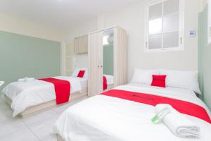 - 2 lits dans une chambre blanche aux accents rouges dans l'établissement RedDoorz Syariah near GOR Bung Karno Nganjuk, à Nganjuk