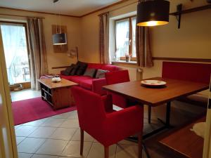 un soggiorno con divano rosso e tavolo di ciao-aschau Grenzhub FeWo 206 Puhlmann a Aschau
