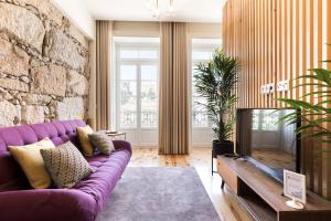 sala de estar con sofá púrpura y pared de piedra en Wine Luxury House, en Oporto