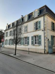 a large white building with green shutters on a street at La Mansarde in Remiremont