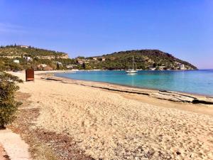 a sandy beach with a boat in the water at Golden Coast Panagias Apartment in Volos