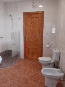 uma casa de banho com um WC, um chuveiro e uma porta de madeira em El Fuerte em Benamaurel