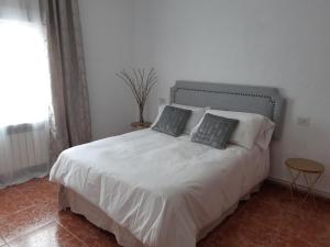 um quarto com uma cama branca com duas almofadas em El Fuerte em Benamaurel