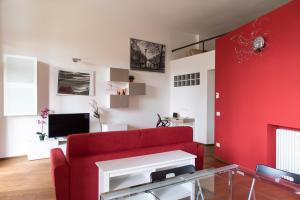 salon z czerwoną kanapą i telewizorem w obiekcie Youhosty - Caviglia 5 w Mediolanie