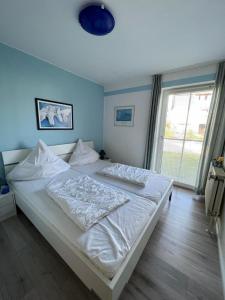 ein weißes Bett in einem Zimmer mit einem großen Fenster in der Unterkunft "Haus Sonnenschein - Whg 3" familiengerechte Wohnung mit 2 SZ und Terrasse in zentraler Lage in Grömitz