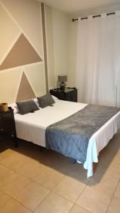 a bedroom with a large white bed with two pillows at Hostal Alhaja Playa in El Puerto de Santa María