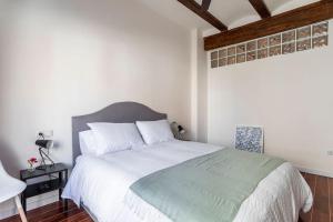 um quarto com uma grande cama branca e piso em madeira em 7P céntrico piso con encanto em Valência