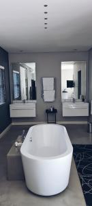 uma grande banheira branca numa casa de banho com três espelhos em Cottage in Sandton em Joanesburgo