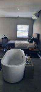 eine weiße Badewanne in einem Schlafzimmer mit einem Bett in der Unterkunft Cottage in Sandton in Johannesburg