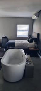 eine weiße Badewanne in einem Schlafzimmer mit einem Bett in der Unterkunft Cottage in Sandton in Johannesburg + 7 Fotos