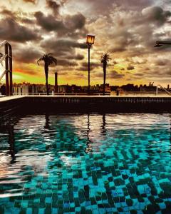 a large swimming pool with a sunset in the background at Modernidade e conforto para sua hospedagem !!! in Sao Paulo