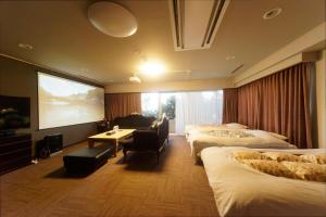 una camera d'albergo con tre letti e un grande schermo di 熱海の隠れ里 ad Atami